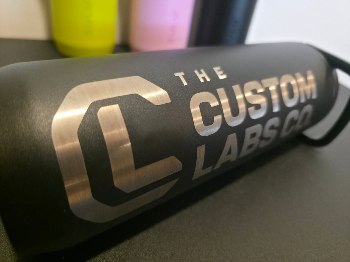 Actual Custom Labs Co. laser engraving shown close-up on a black Zulu bottle lying sideways